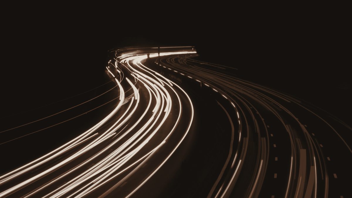 Long-exposure light trails curving through darkness